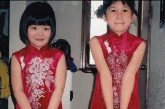 Deux petites filles vêtues de belles robes de soie rouge.